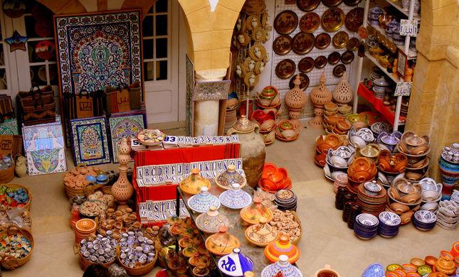 Colorful handmade ceramics, bowls and tagines displayed inside a Tunis Village pottery shop