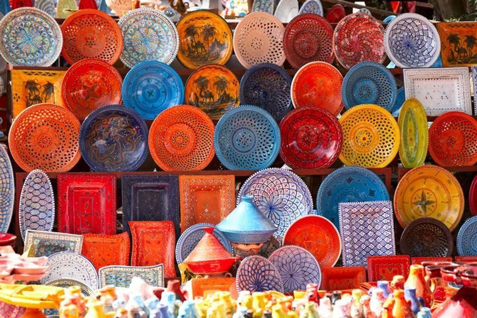 Vibrant hand-painted ceramic plates and trays for sale at a Tunis Village pottery stall