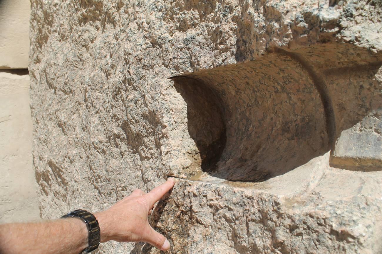 A hand pointing to a carved circular socket in the granite of the Unfinished Obelisk