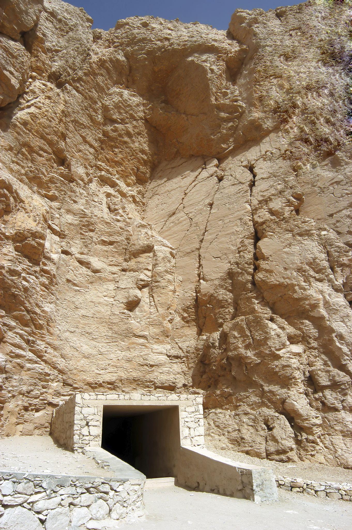 Small stone-framed tomb entrance set into a towering cliff face in the Valley of the Kings.
