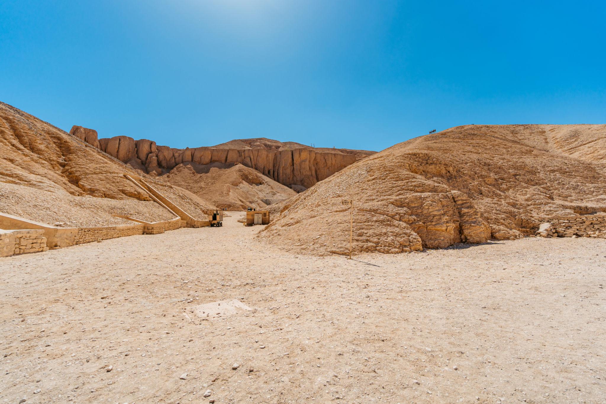 Wide view of the arid Valley of the Kings with sandy paths and surrounding Theban hills.