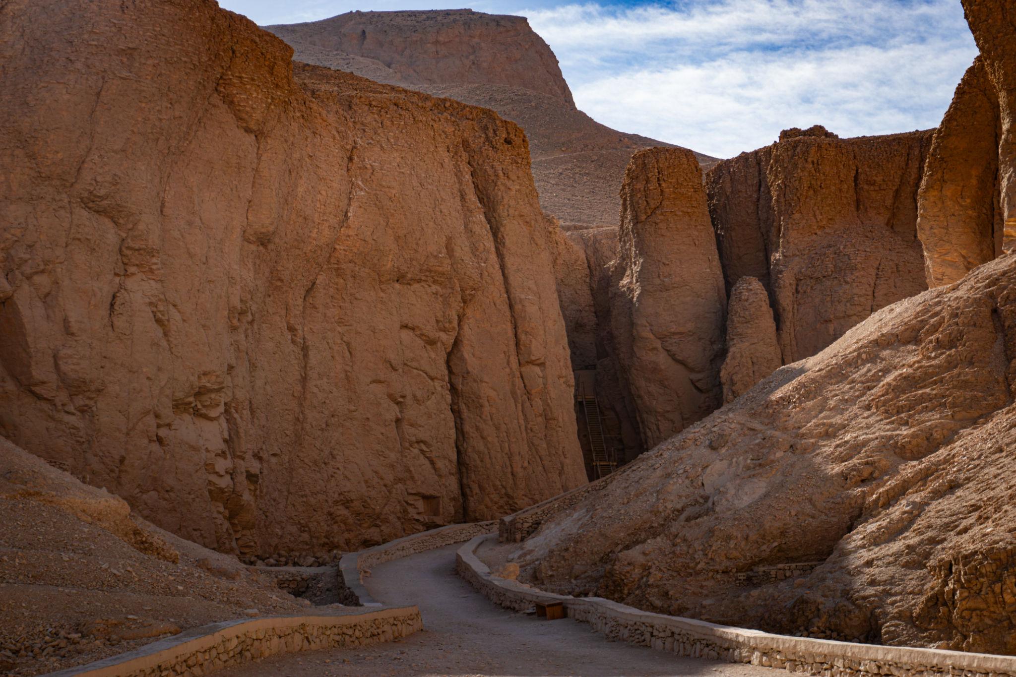 Winding path through steep red desert cliffs leading to tombs in the Valley of the Kings.