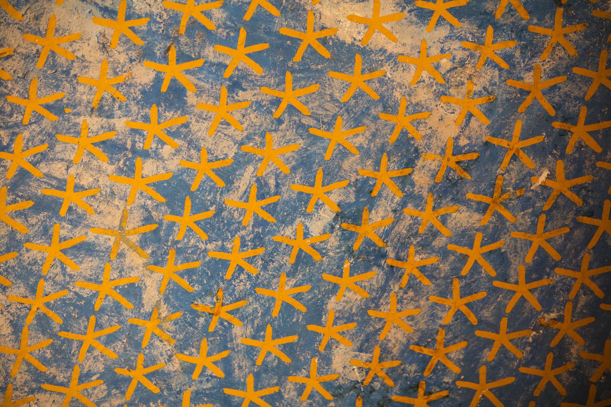 Close-up of a painted ceiling covered in golden five-pointed stars on a deep blue background.