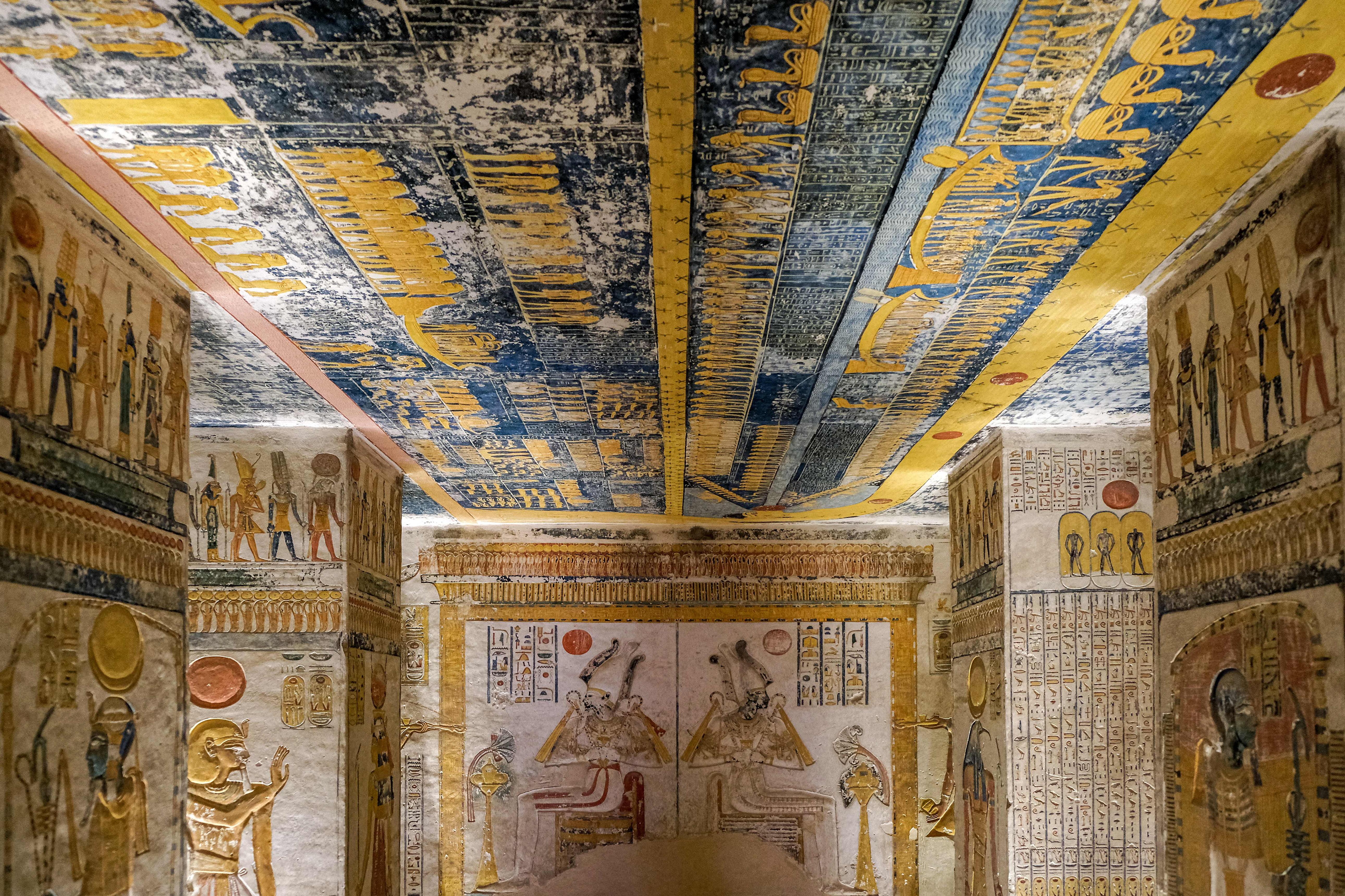 Pillared tomb hall with vivid painted columns and a starry blue and yellow ceiling.