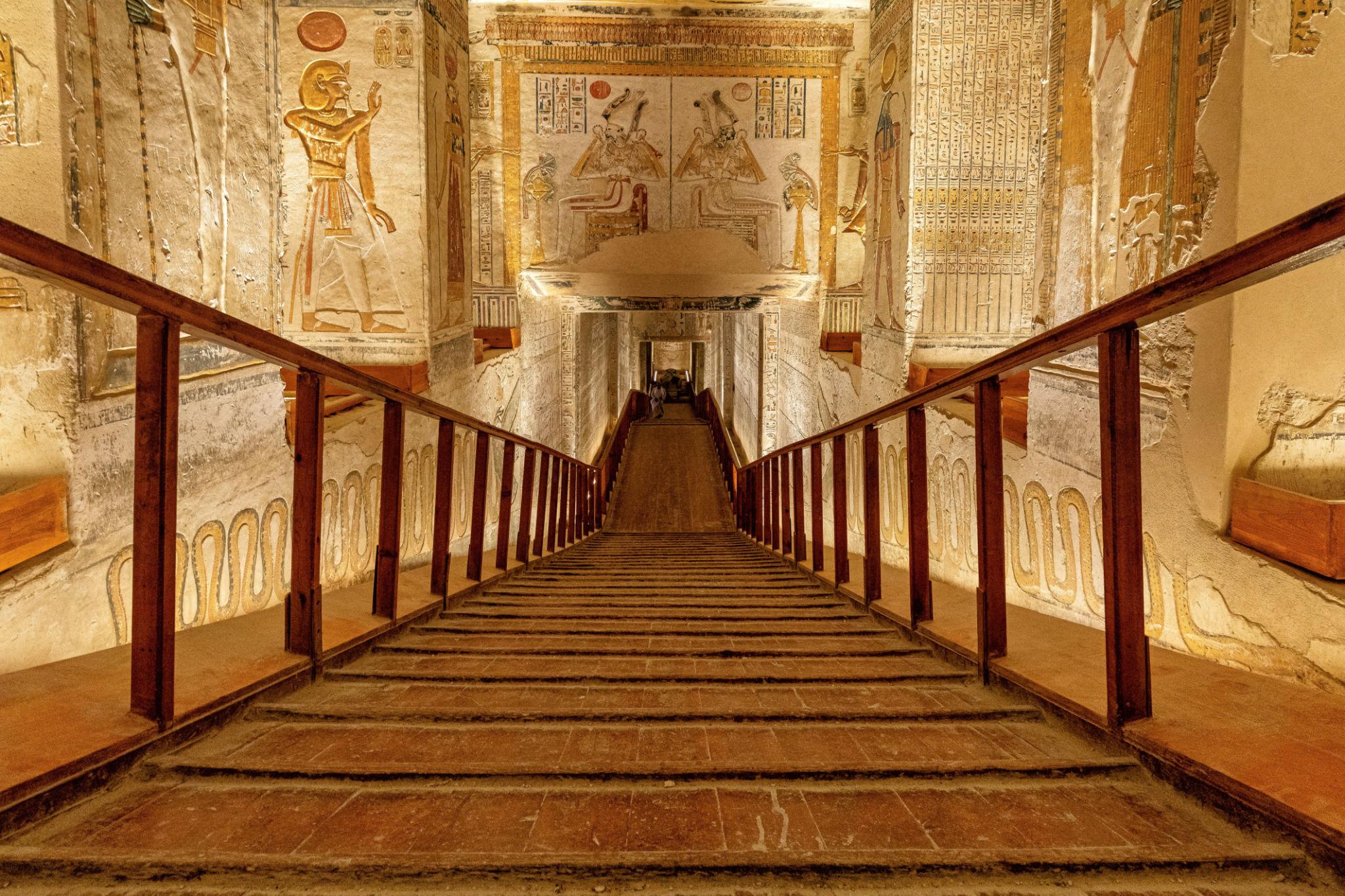 Staircase flanked by painted reliefs of Ramesside kings and deities inside a royal tomb.