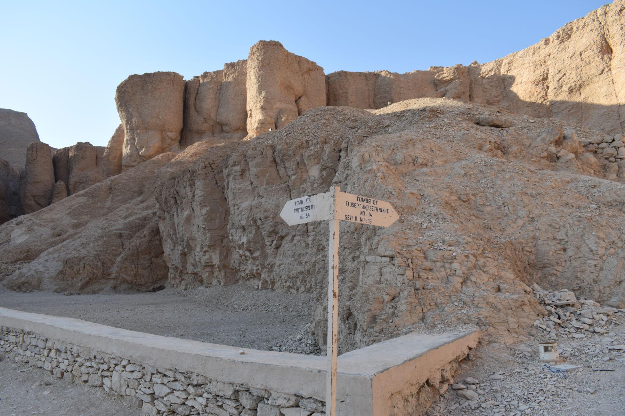 Directional signpost among rocky terrain pointing visitors to tombs in the Valley of the Kings.