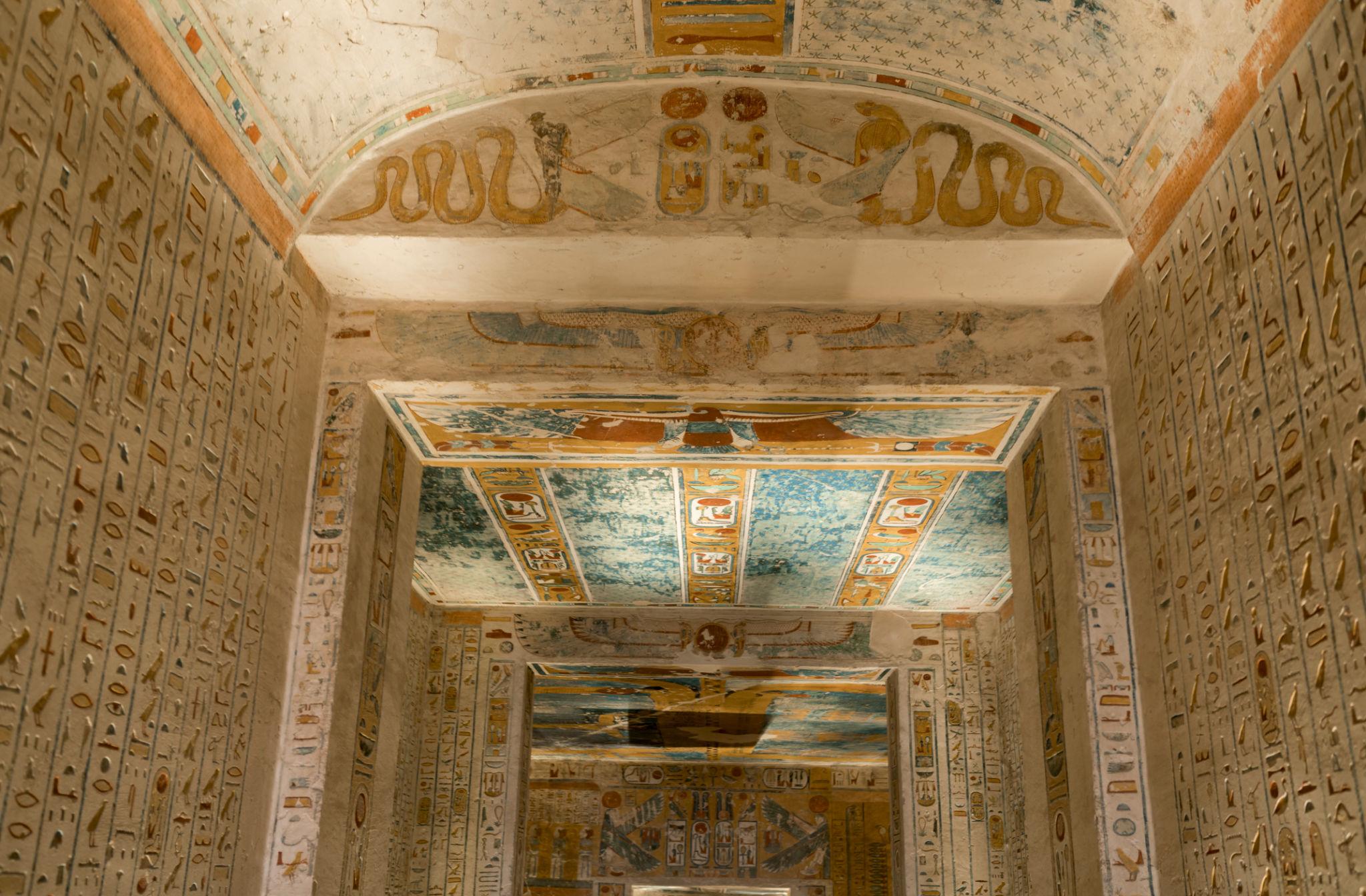 Vaulted burial chamber with hieroglyph-covered walls and astronomical ceiling in a royal tomb.