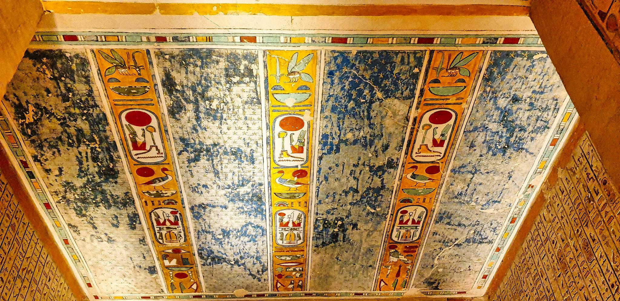 Painted ceiling with royal cartouches on a weathered blue and yellow background.
