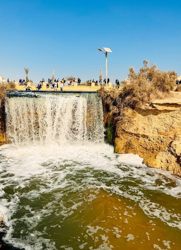 Visitors gathered above the foaming Wadi El Rayan waterfall
